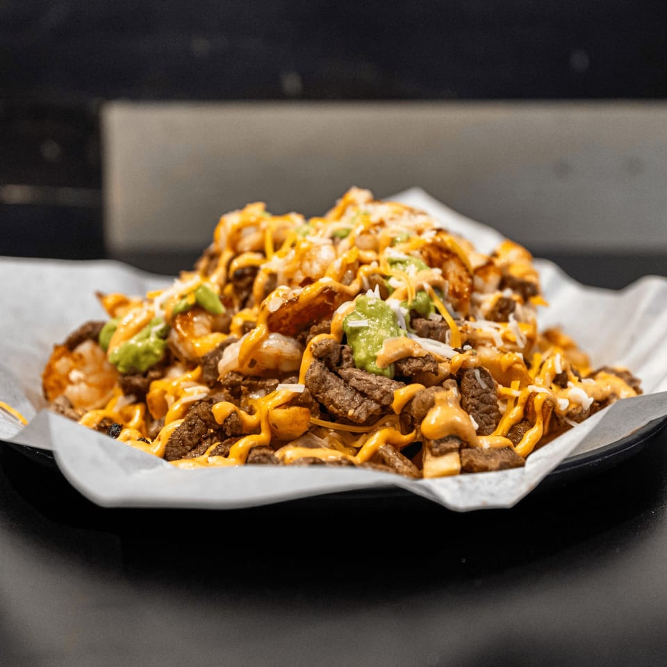 El Burrito Taco Shop's carne asada fries, topped with cheese, guacamole, and a creamy sauce.