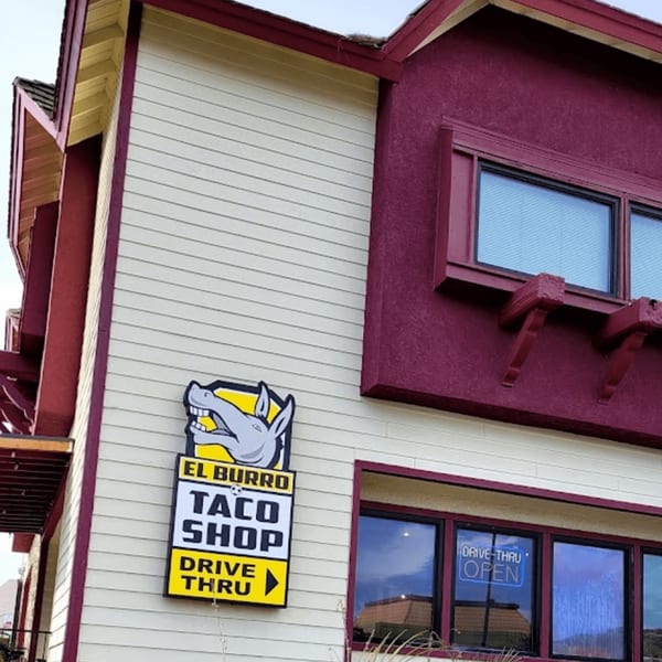 Exterior of El Burrito Taco Shop, a white and maroon building with a drive-thru sign.