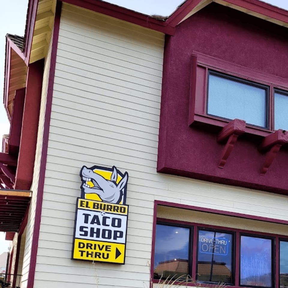 Exterior of El Burrito Taco Shop, a white and maroon building with a drive-thru sign.