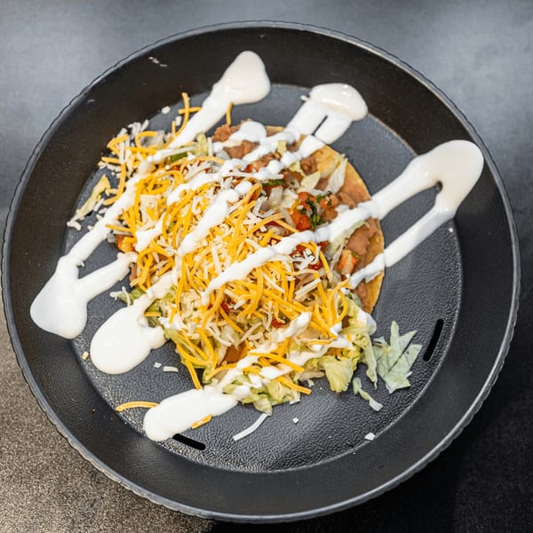 El Burrito Taco Shop's tostada, topped with beans, lettuce, cheese, pico de gallo, and sour cream.