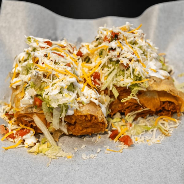 A large El Burrito Taco Shop burrito, cut in half, topped with lettuce, cheese, and sour cream.